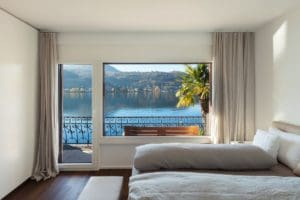 A bedroom with a large window overlooking the water.